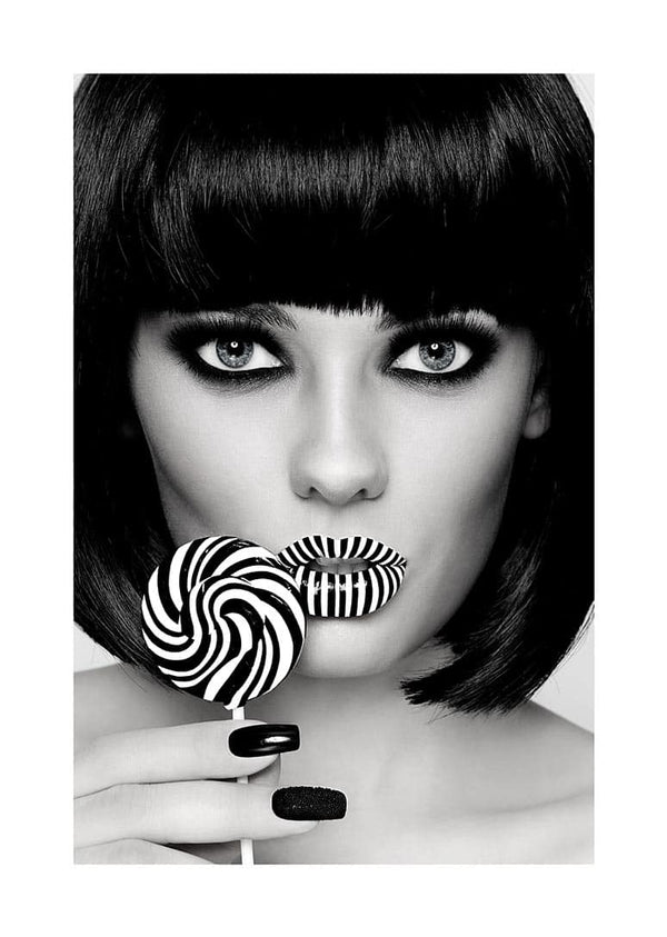 Stylish woman with bold makeup holding a matching black and white striped lollipop near her lips.