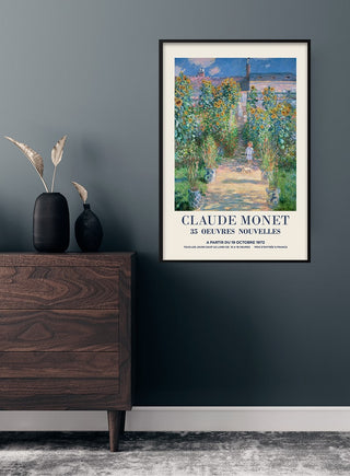 Framed Claude Monet kunstenerens have poster on a dark wall above a wooden dresser with decorative vases.