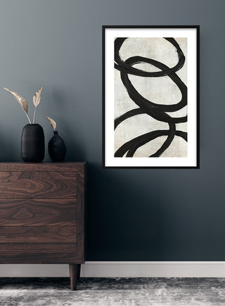 Black circle kunstposter featuring abstract black loops on a white background, framed and hung above a wooden dresser.