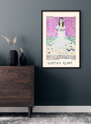 Framed Gustav Klimt Mäda Primavesi poster on a gray wall above a wooden dresser with vase and dried plants.