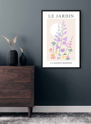 Framed Le Jardin no. 1 Plakat with pastel flowers and sun, hanging above a wooden dresser in a modern room.