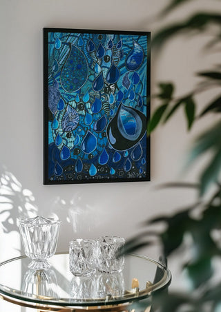 Blue Raindrops by JHN.ByHjort in a black frame above a glass table with crystal glassware