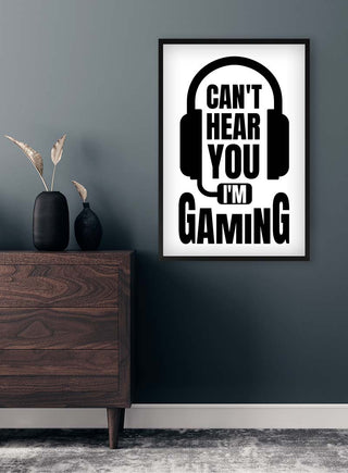 Framed "Can't Hear You I'm Gaming" poster with headset graphic on wall above a dark wooden dresser.