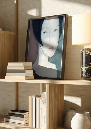 A Child by Designus in a dark frame on a wooden shelf beside books and a lamp