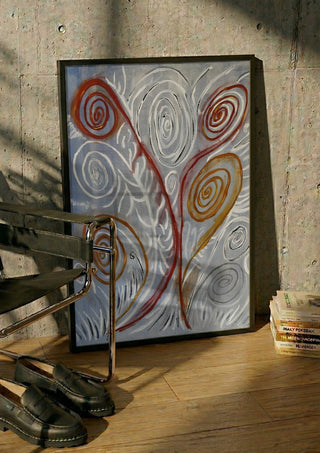 Coil by Fábio Diniz Art in a black frame leaning against a concrete wall by a steel chair