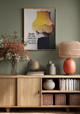 Solsken by Grafik bageri above a wooden sideboard on a sage green wall