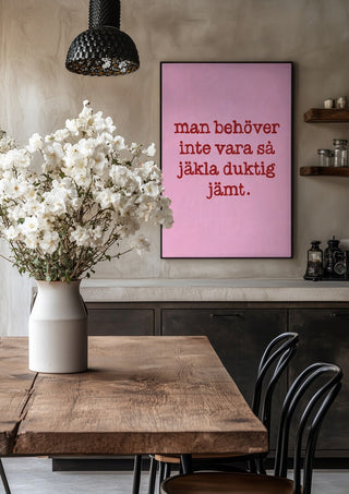 Duktig jämt by Grafik bageri in a black frame above a rustic table with white flowers