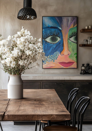 Blue and Green Face by Camilla Sabrina in a black frame above a rustic table with white flowers