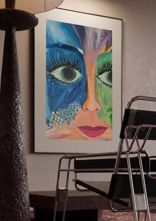 Blue and Green Face by Camilla Sabrina framed in a dim room beside a tubular steel chair