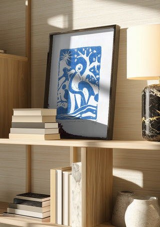 Schnitt durch den Hain · Cut Through the Grove by ELIZA Leopold in a dark frame on a wooden shelf beside books and a lamp
