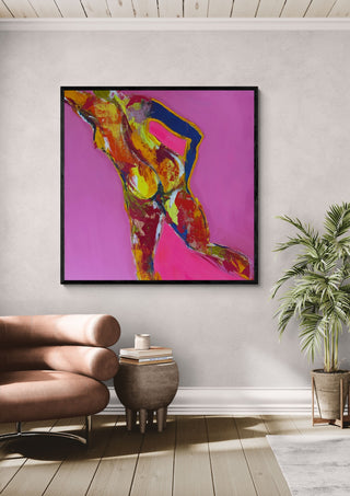 Pink Nude by René J in a black frame above a tan leather chair beside a potted plant