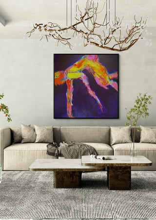 Leap by René J in a black frame above a beige sofa under a branch chandelier