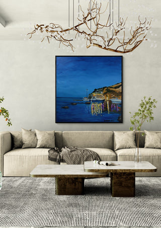 Evening Boats by Nella Hajdu in a black frame above a beige sofa under a branch chandelier