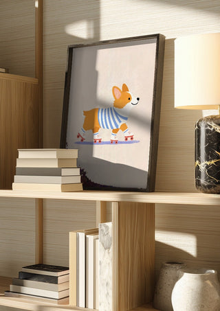 Corgi on Roller Skates by Decker Studios in a dark frame on a wooden shelf beside books and a lamp