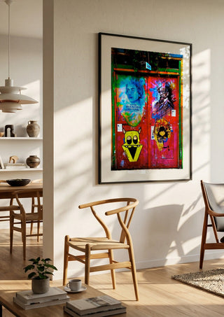 Graffiti Door by Pelecan Schneider in a black frame in a bright dining room with wooden chairs