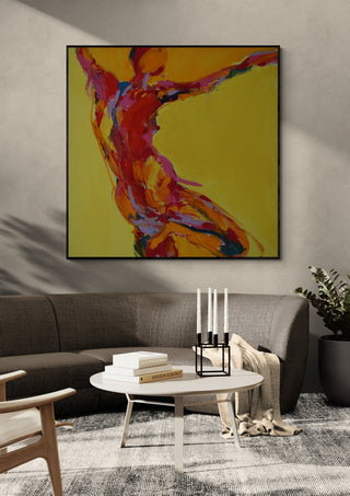 Reaching Figure by René J in a black frame above a grey sofa with a round coffee table and candlesticks