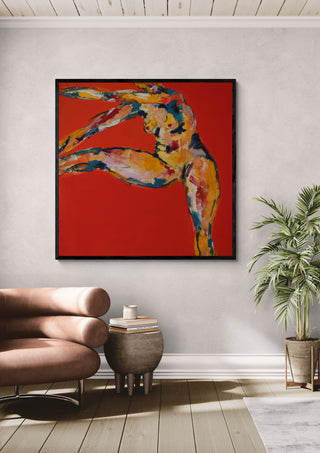 Arch in Red by René J in a black frame above a tan leather chair beside a potted plant