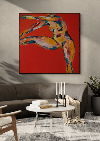Arch in Red by René J in a black frame above a grey sofa with a round coffee table and candlesticks