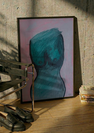 Kroppen by RR in a black frame leaning against a concrete wall by a steel chair