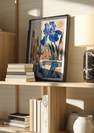 The Blue Garden by Matthews Gallerie in a dark frame on a wooden shelf beside books and a lamp