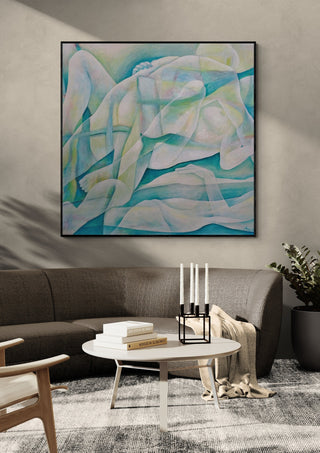 The Creation of the World by Andreas Pohle in a black frame above a grey sofa with a round coffee table and candlesticks