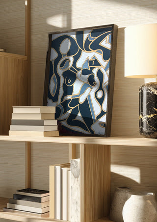 Erotica by Andreas Pohle in a dark frame on a wooden shelf beside books and a lamp