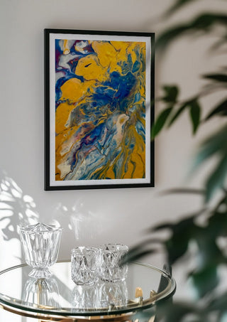 Gold and Indigo by Da Winters in a black frame above a glass table with crystal glassware
