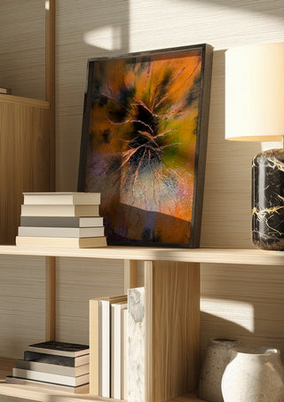 Copper Branches by Da Winters in a dark frame on a wooden shelf beside books and a lamp