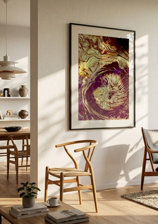 Plum Bloom by Da Winters in a black frame in a bright dining room with wooden chairs