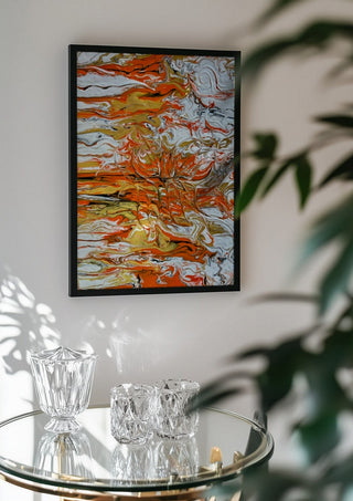 Orange Tide by Da Winters in a black frame above a glass table with crystal glassware
