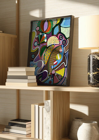 Peaceful Power by LGDyrby in a dark frame on a wooden shelf beside books and a lamp