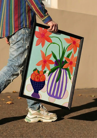 Plums & Peace by LGDyrby carried in a black frame along a sunny street