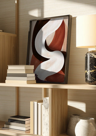 Curve in Cream by Martina Karlsson in a dark frame on a wooden shelf beside books and a lamp