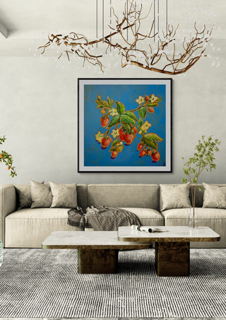 Strawberries on Blue by Svetla Stoyanova Bassi in a black frame above a beige sofa under a branch chandelier