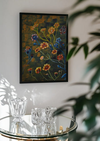 Field Flowers in Olive by Svetla Stoyanova Bassi in a black frame above a glass table with crystal glassware
