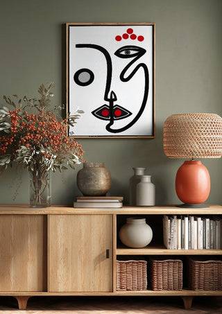 Face by RA above a wooden sideboard on a sage green wall