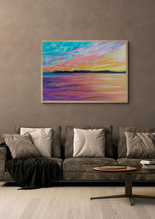 Colours of the Sky by Finbar Stevens in a light wood frame above a grey sofa with cushions