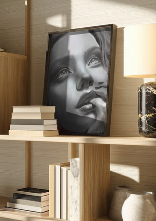 the dreamer by Sofia de Lemos in a dark frame on a wooden shelf beside books and a lamp