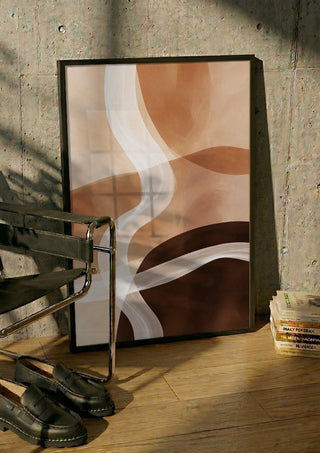 Sand and Clay by Martina Karlsson in a black frame leaning against a concrete wall by a steel chair