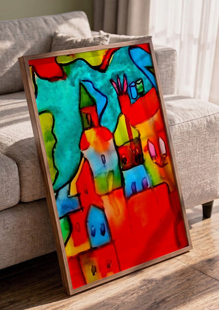 The Village by Nittaart in a walnut frame leaning against a grey sofa