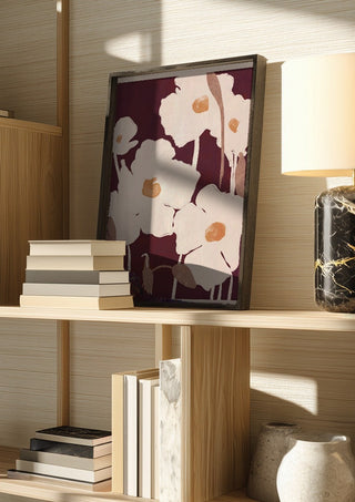 Abstract Flowers 10 by ThingDesign in a dark frame on a wooden shelf beside books and a lamp