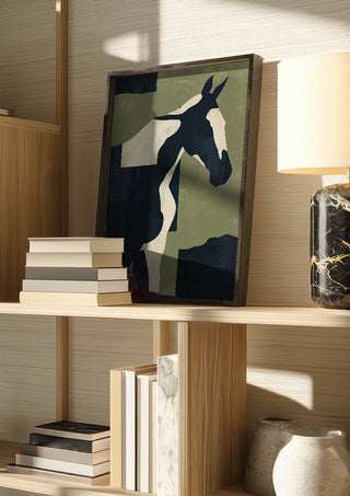 Abstract Minimal Horse 4 by ThingDesign in a dark frame on a wooden shelf beside books and a lamp