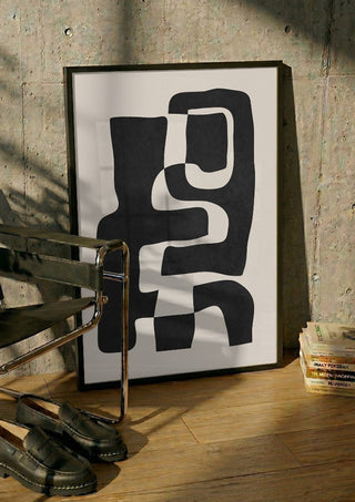 Abstract Art 55 by ThingDesign in a black frame leaning against a concrete wall by a steel chair