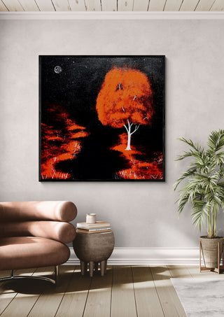 Red Tree by Moonlight by Marcel Herrmann in a black frame above a leather armchair beside a palm
