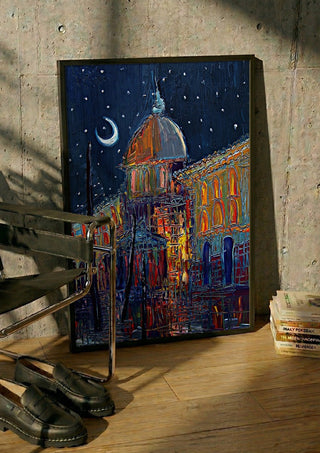 Crescent Moon over the City by Justyna Kopania in a black frame leaning against a concrete wall by a steel chair