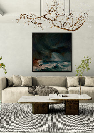 Storm over the Breakers by Justyna Kopania in a black frame above a cream sofa under a branch chandelier