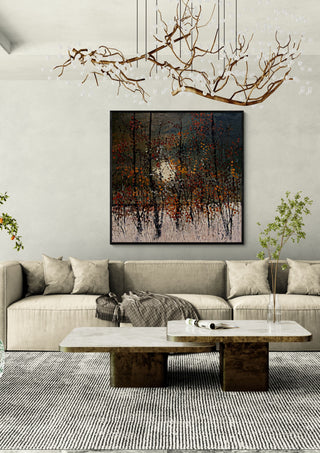Autumn Trees in the Sun by Justyna Kopania in a black frame above a cream sofa under a branch chandelier