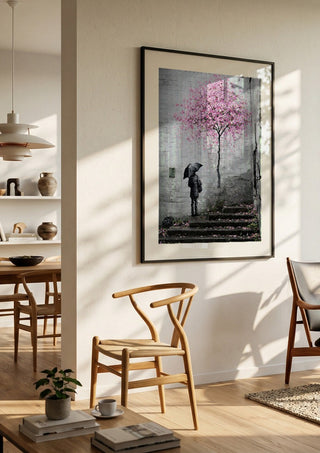 Spring x Banksy by Decker Studios in a black frame in a bright dining room with wooden chairs