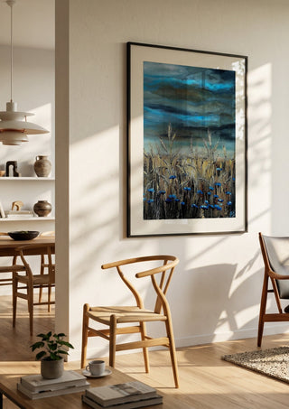 Blue fields by Lüba in a black frame in a bright dining room with wooden chairs