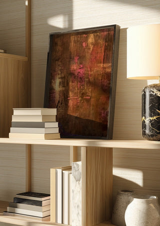 Copper and Rose by Kristof ellertz in a dark frame on a wooden shelf beside books and a lamp